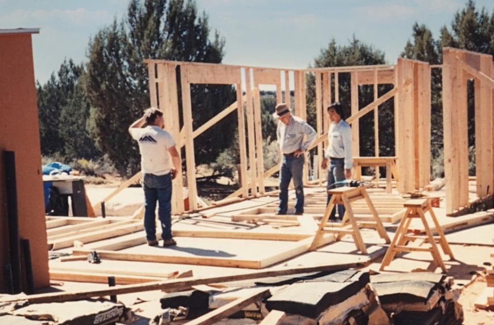 old photo of 3 people and building construction